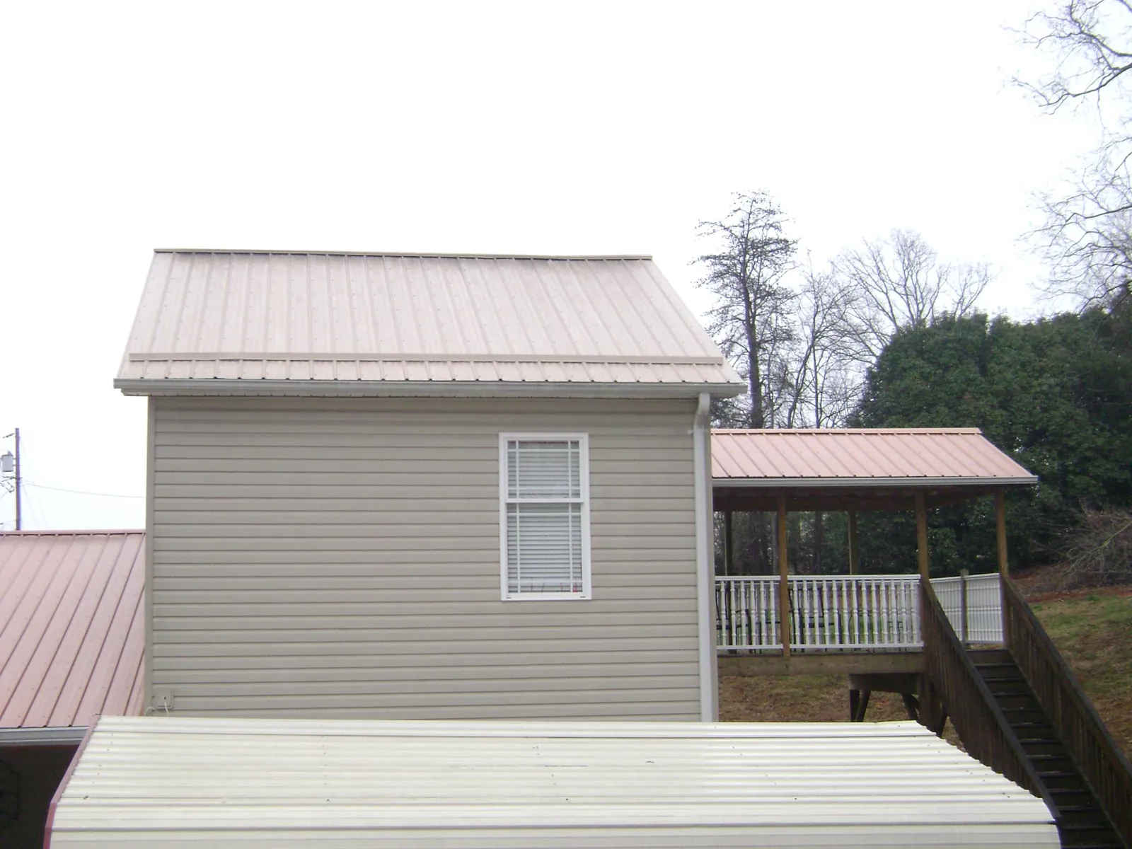 Tan metal roofs on a two story addition and attached porch, from a Roof Replacement job in Fairfax