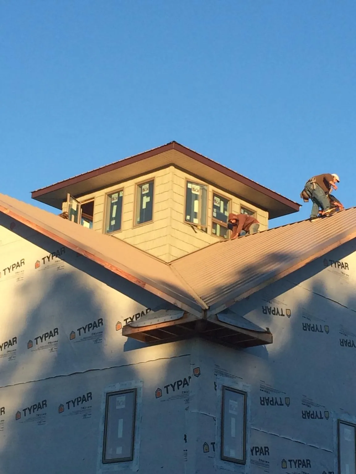 Roofers working around a rooftop cupola on a new metal roof at sunset — Roof Waterproofing in Fairfax by Roofing Brothers